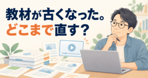 机の上の講座資料とパソコンの動画を見ながら、古くなった教材をどこまで直すか考える講師